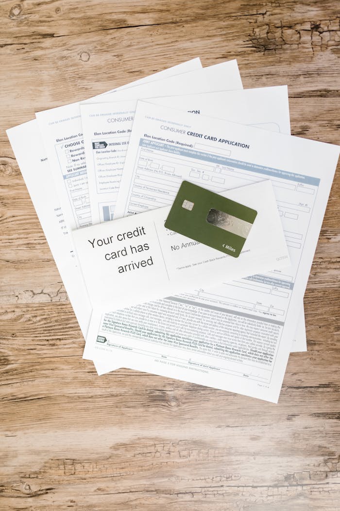 Top view of credit card with application forms and letter on a wooden desk.