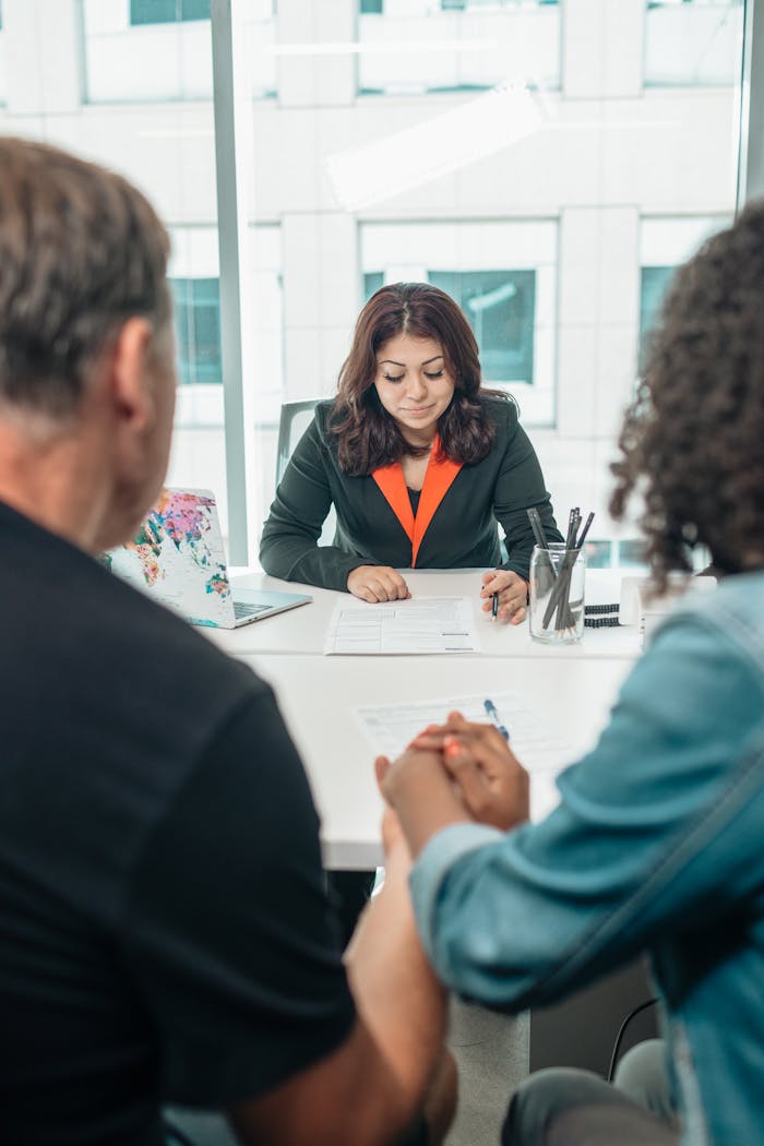 A couple signing adoption papers in an office with a lawyer's assistance.